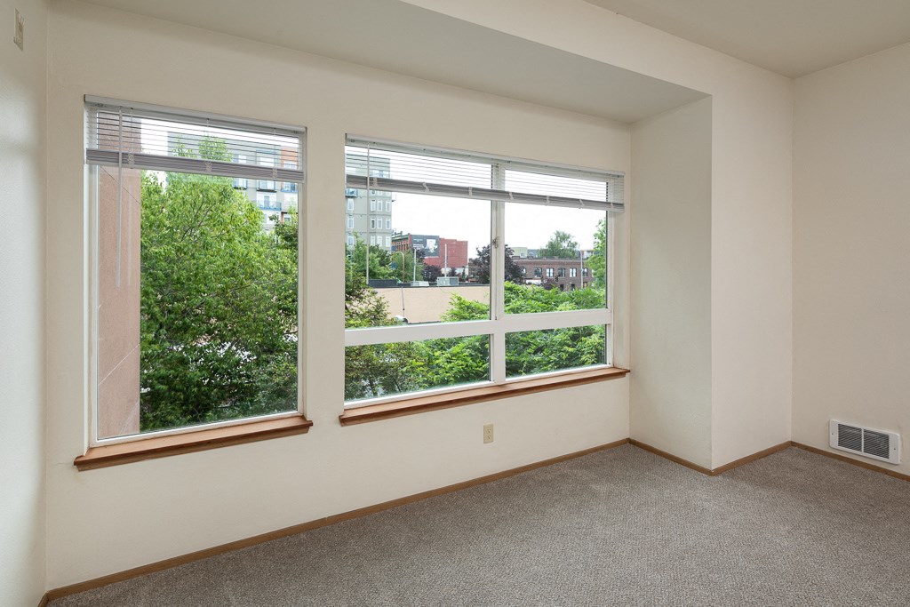 an empty room with large windows and a carpeted floor
