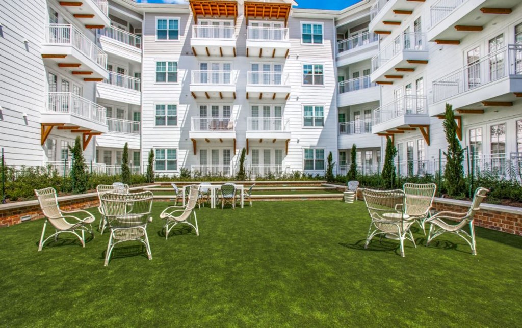 a courtyard with chairs and tables in front of an apartment building