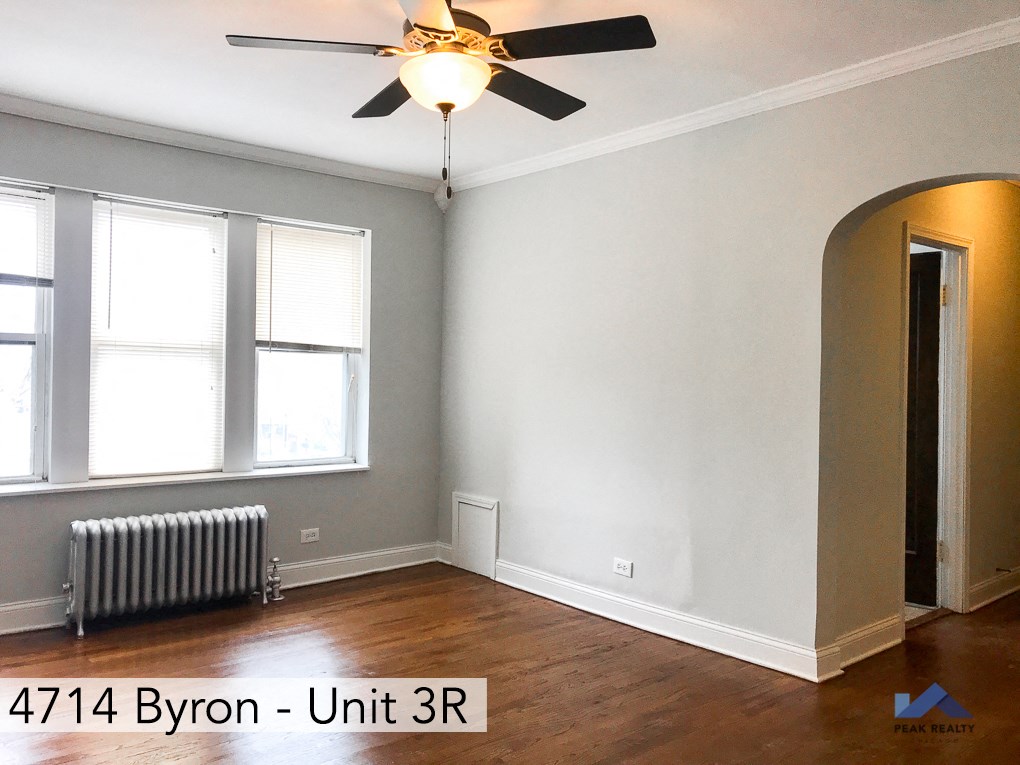 an empty room with a ceiling fan and a radiator
