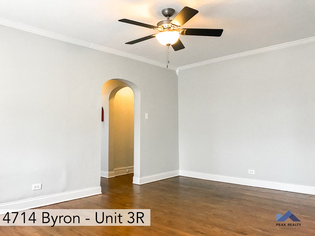 a living room with white walls and a ceiling fan
