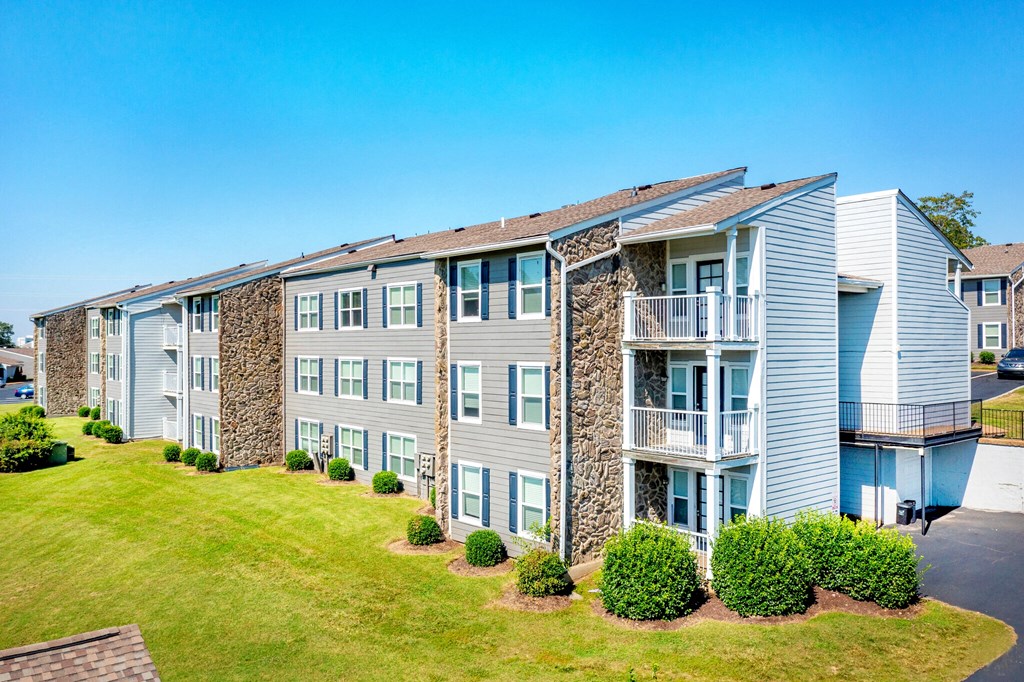 an exterior view of an apartment building with green grass and shrubs