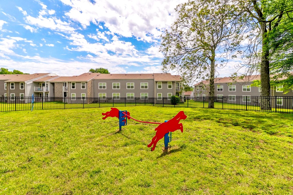 two kites flying in a field in front of an apartment building
