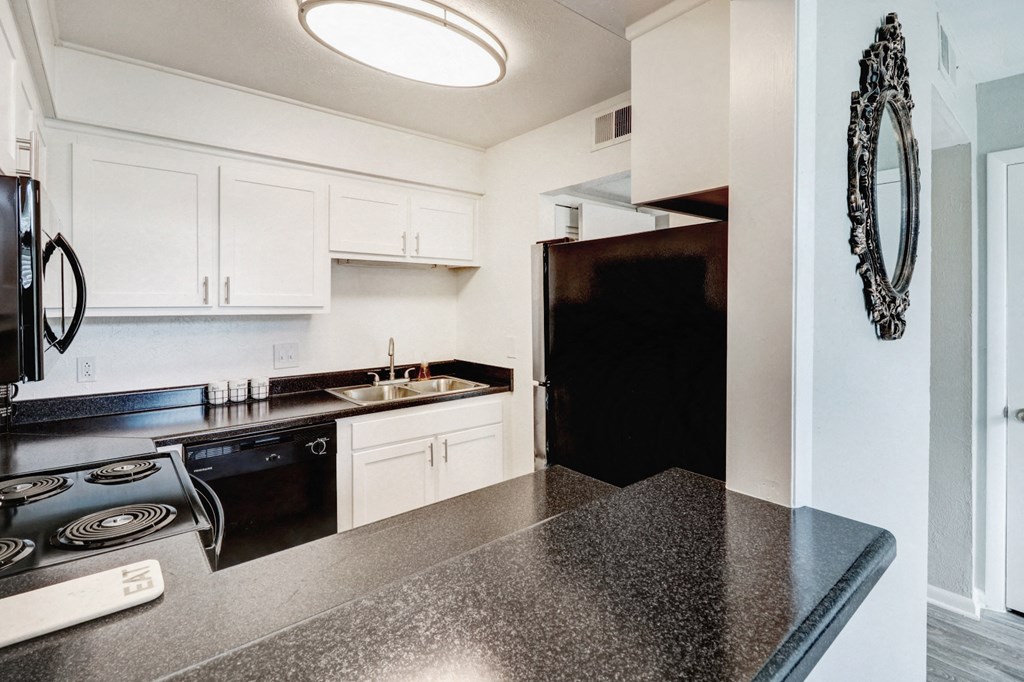 a kitchen with white cabinets and black counter tops and a black refrigerator