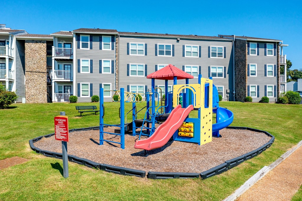 a playground in front of an apartment building with a red slide