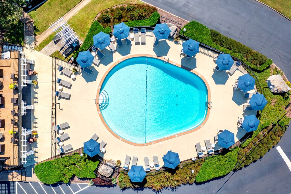 an overhead view of a swimming pool with chairs and umbrellas