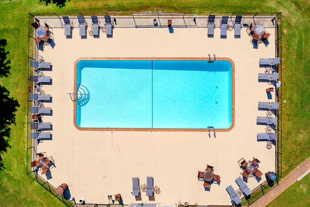 an aerial view of a swimming pool with lounge chairs around it