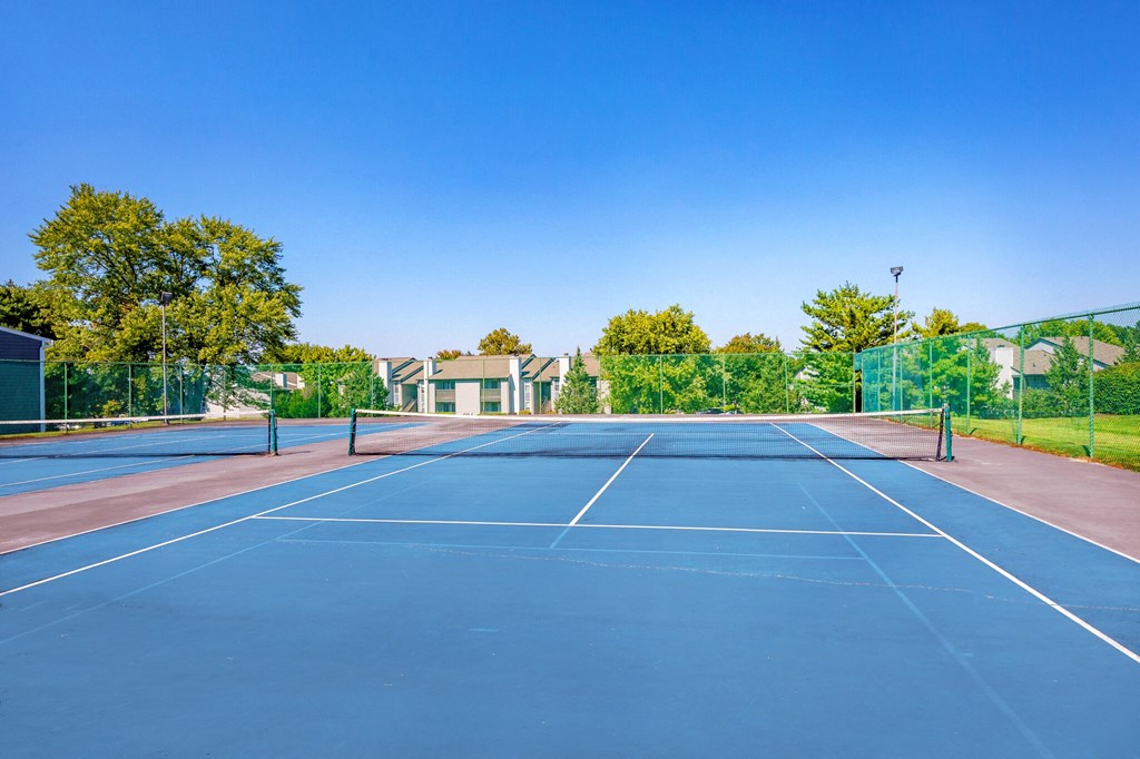 the tennis court is equipped with a blue court and a fence