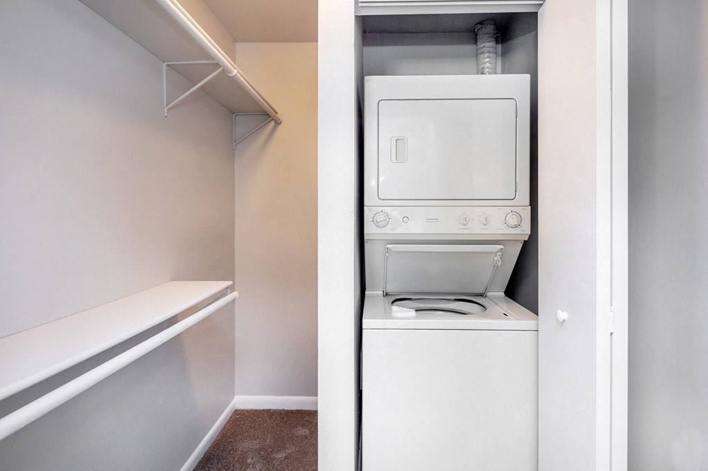 an empty closet with a washer and dryer in it and a white refrigerator