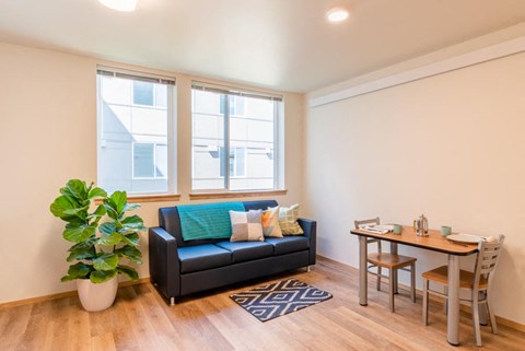 A living room with a black couch and a wooden table.