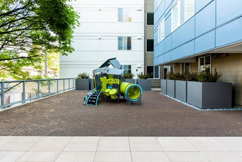 A playground with a slide and a yellow barrel.