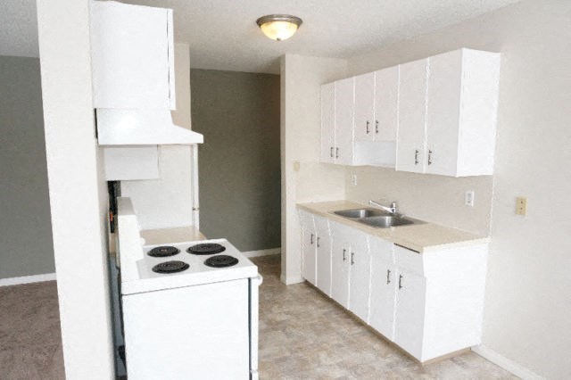 an empty kitchen with a stove and a sink