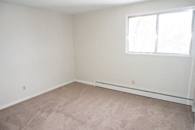 an empty room with a window and a carpeted floor