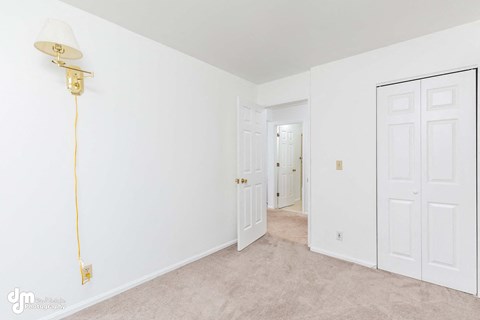 a bedroom with white walls and white doors and a lamp