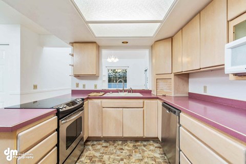 a kitchen with pink counter tops and wooden cabinets