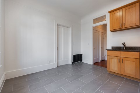 A kitchen with wooden cabinets and a grey tile floor.