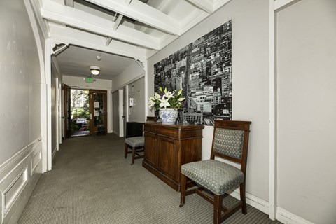A hallway with a chair and a cabinet with a vase of flowers on top.