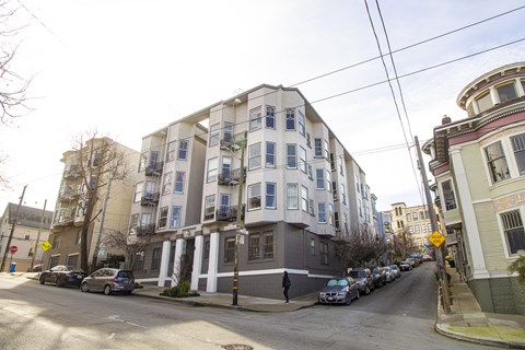 A street view of a residential area with cars parked on the side of the road.