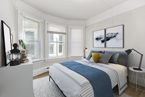A bedroom with a bed, a chair, and a painting on the wall.