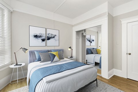 A bedroom with a bed, two lamps, and a painting on the wall.