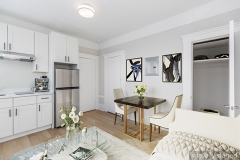 A kitchen with white cabinets and a dining table with chairs.