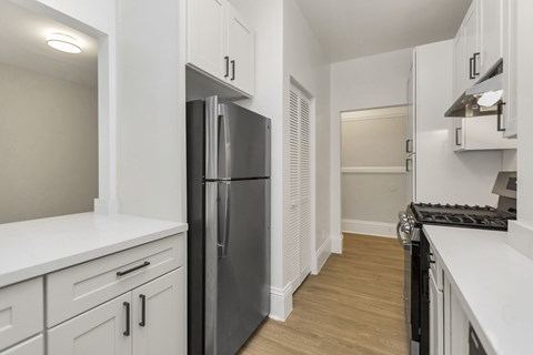 A kitchen with white cabinets and a black fridge.