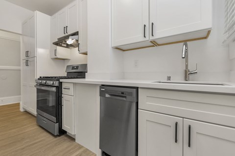 A modern kitchen with white cabinets and stainless steel appliances.