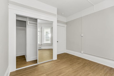 A room with a mirror on the wall and wooden flooring.