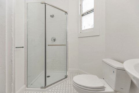 A white bathroom with a toilet, sink, and shower.