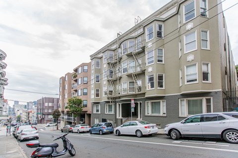 A street view of a residential area with cars parked on the side of the road.