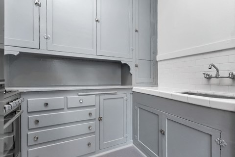 A kitchen with white cabinets and a grey counter.