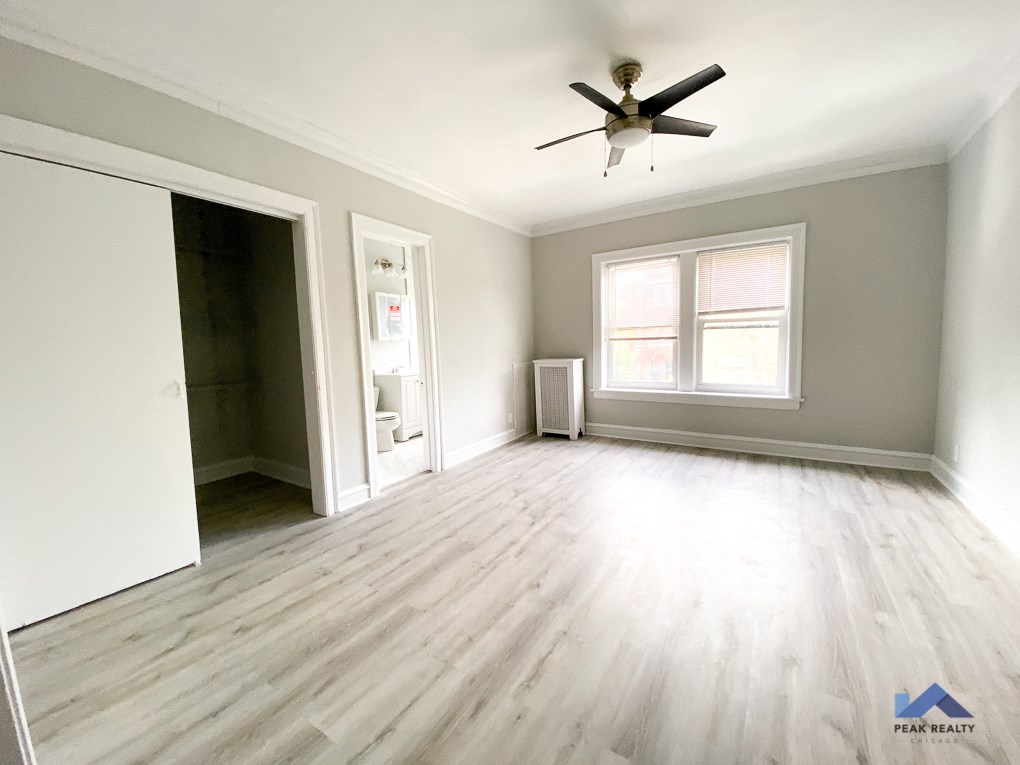 an empty living room with hardwood floors and a ceiling fan