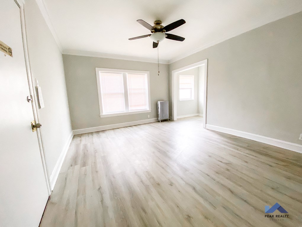 an empty living room with hardwood floors and a ceiling fan