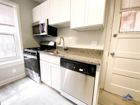 a kitchen with white cabinets and a black dishwasher and a counter top