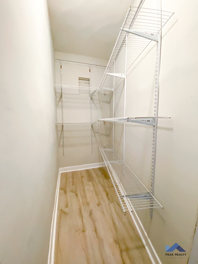 a walk in closet with white walls and a wood floor
