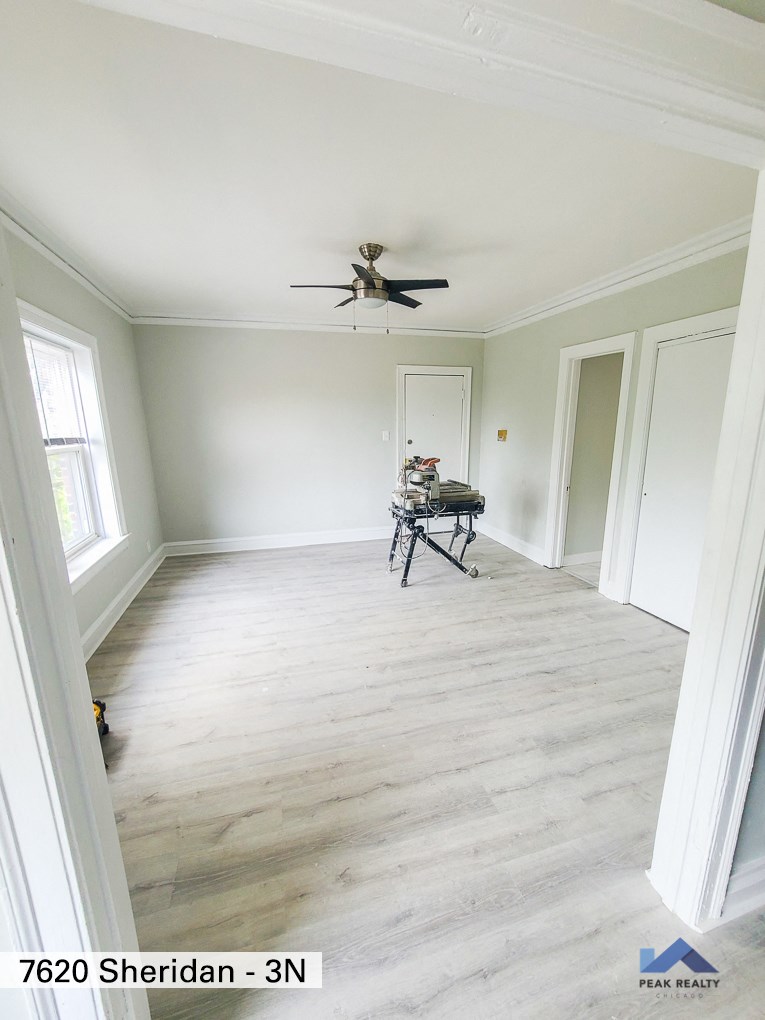 an empty living room with white walls and a ceiling fan