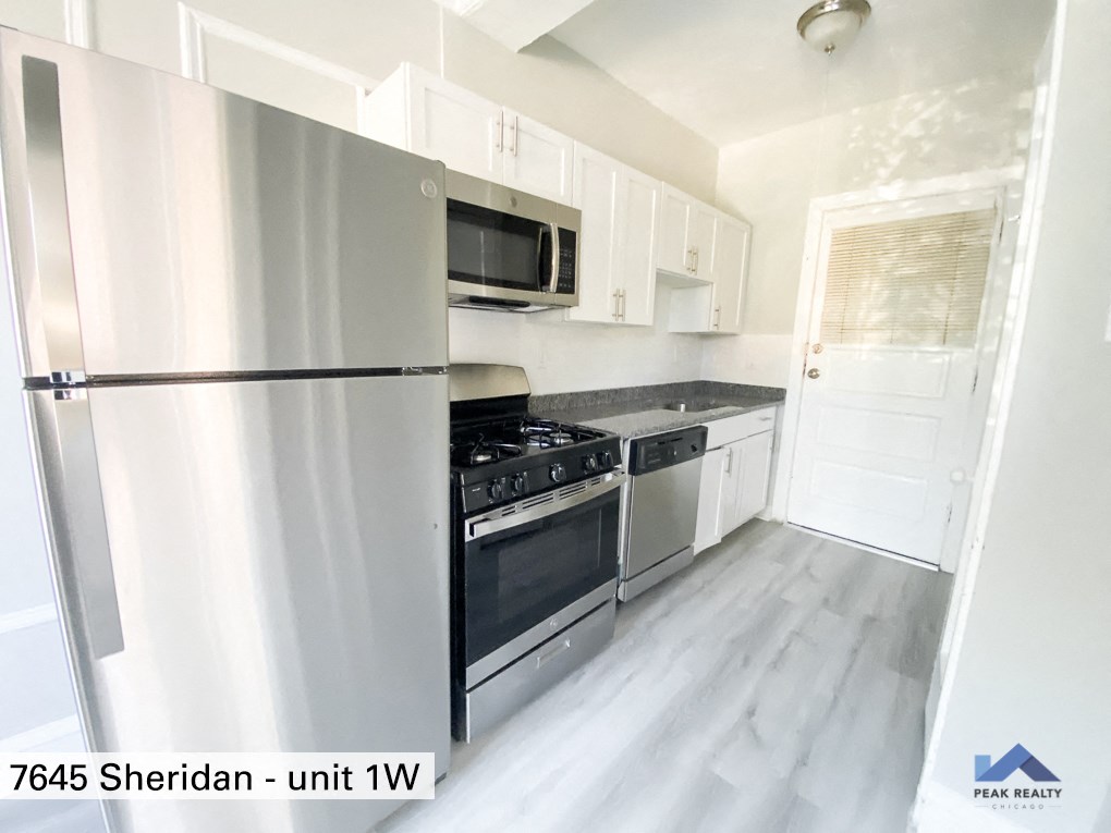 an empty kitchen with stainless steel appliances and white cabinets