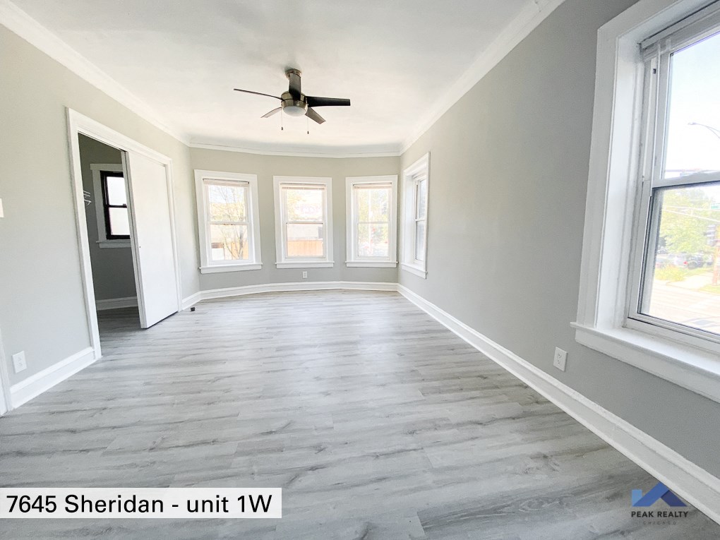 an empty living room with a ceiling fan and windows