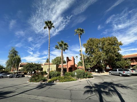 a parking lot with palm trees and a building