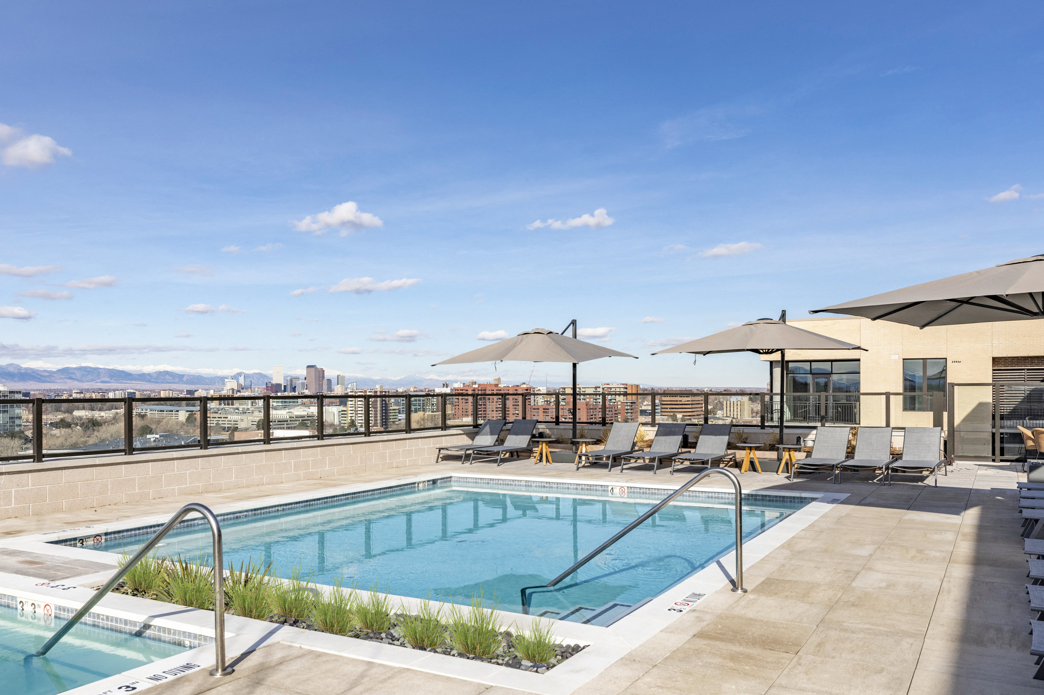 the pool on the rooftop of a building with chairs and umbrellas