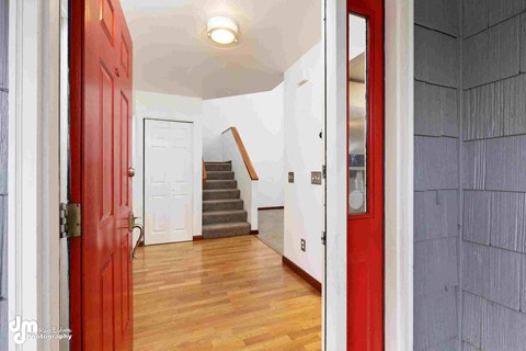 a renovated living room with a red door and a staircase