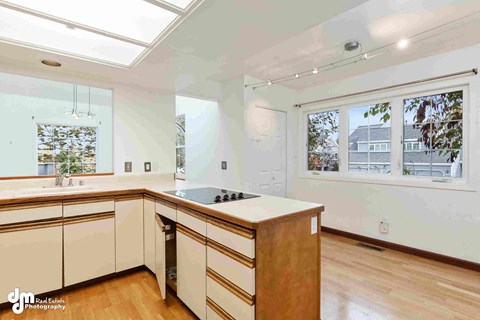 an updated kitchen with white cabinets and a large window