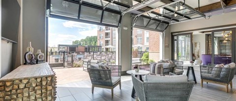 a living room with patio furniture and large windows