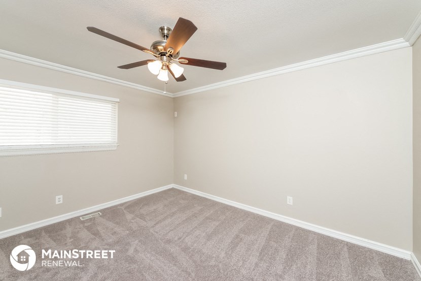 the bedroom has a ceiling fan and carpeted flooring