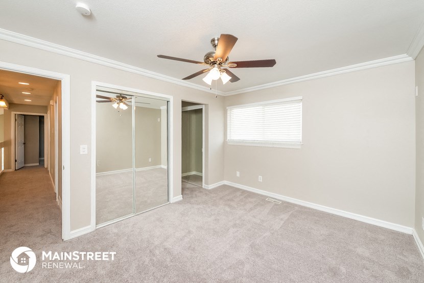 the master bedroom has a mirrored closet and ceiling fan
