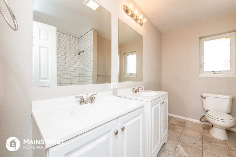 a white bathroom with two sinks and a toilet