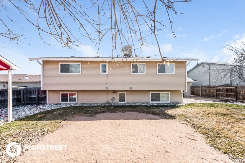 a beige house with a gravel driveway and a yard
