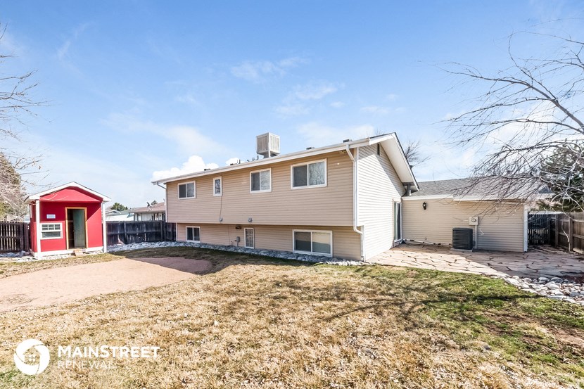 a beige house with a red door and a yard