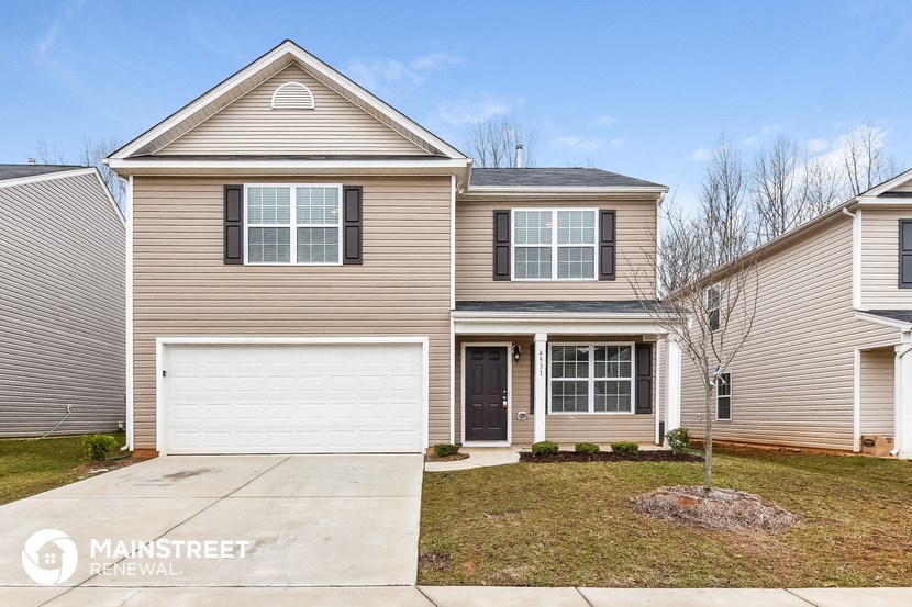 a beige house with a white garage door and a lawn