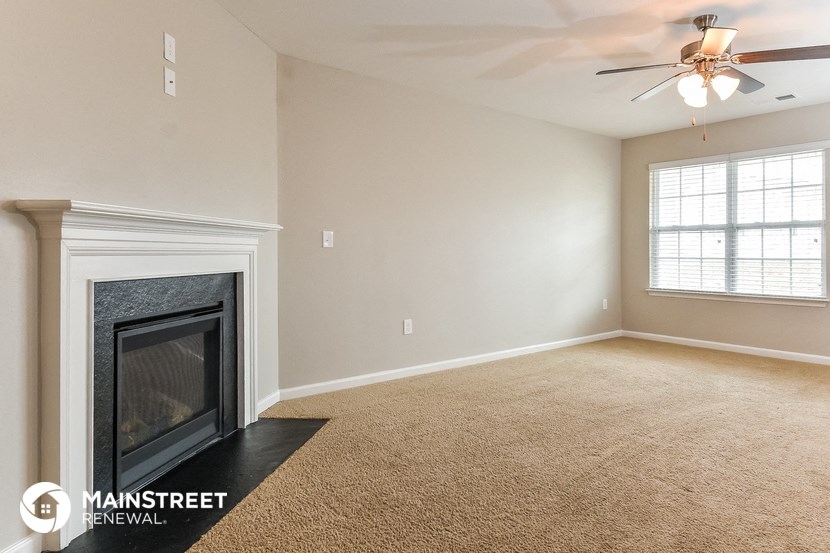 a living room with a fireplace and a ceiling fan