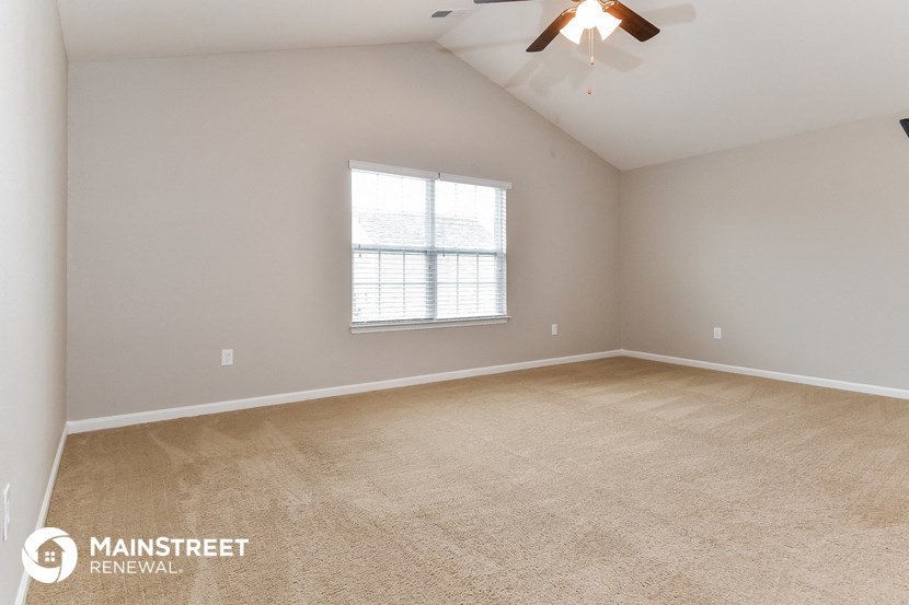 the spacious living room with carpeting and a ceiling fan